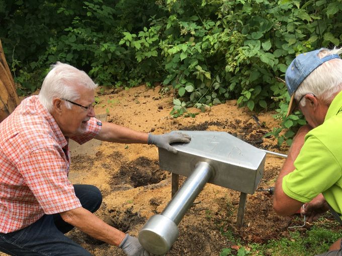2 personer fra 'Onsdagsholdet' er her igang med at forankre Thors Hammer ved siden af den netop nyudskårne udgave af Thor.  (juli 2021)